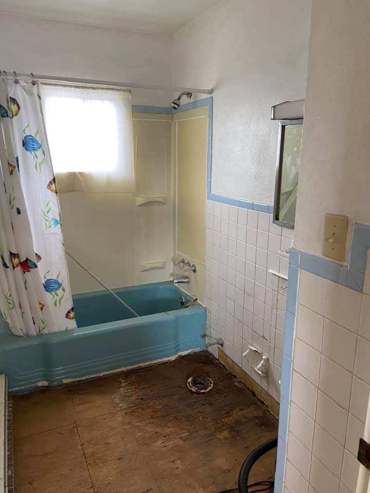 Bathroom before renovation — dated blue suite and bare floor